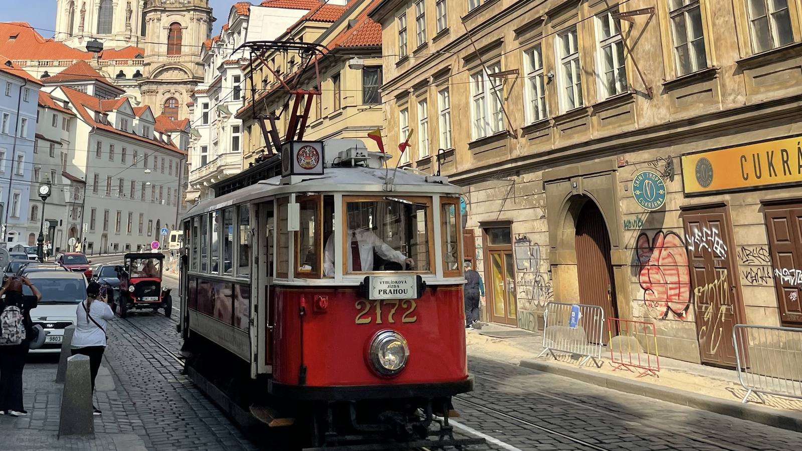 A red heritage tram on a cobbled street in Prague